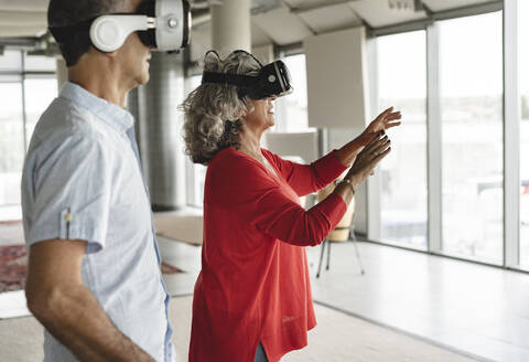 Geschäftskollegen in einem Virtual-Reality-Simulator stehen im Büro - JCICF00199