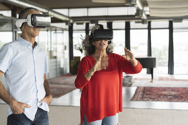 Business colleagues wearing virtual reality simulator gesturing in office - JCICF00201