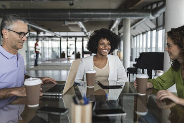 Happy business colleagues sitting together at desk - JCICF00204