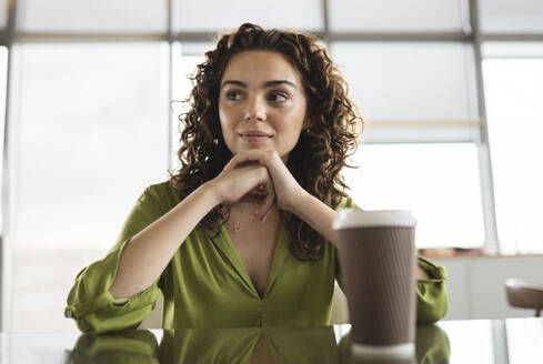 Junge Geschäftsfrau mit Kaffeetasse am Schreibtisch sitzend - JCICF00211
