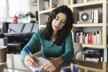 Geschäftsfrau schreibt im Büro in Tagebuch - JCICF00233