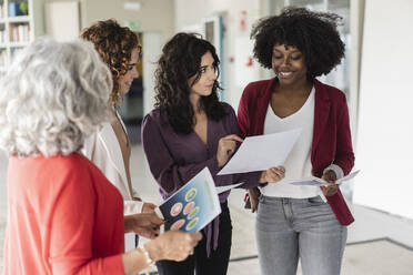 Geschäftsfrauen, die im Büro über Dokumente diskutieren - JCICF00257