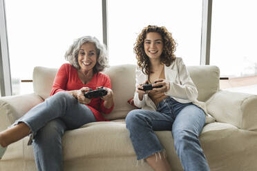 Happy woman with friend playing video games - JCICF00268