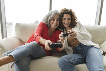 Happy senior woman with friend playing video games - JCICF00269