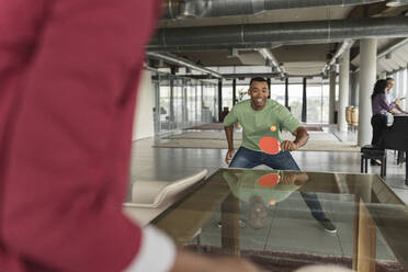 Happy businessman playing table tennis in office - JCICF00270