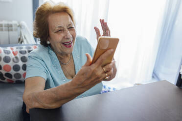 Glückliche ältere Frau, die zu Hause ein Smartphone benutzt - EGHF00462