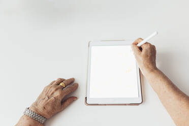 Hände einer älteren Frau mit Tablet-PC auf weißem Hintergrund - EGHF00478