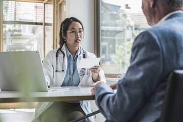 Arzt diskutiert mit Patientin über Verschreibung in medizinischer Klinik - UUF26634