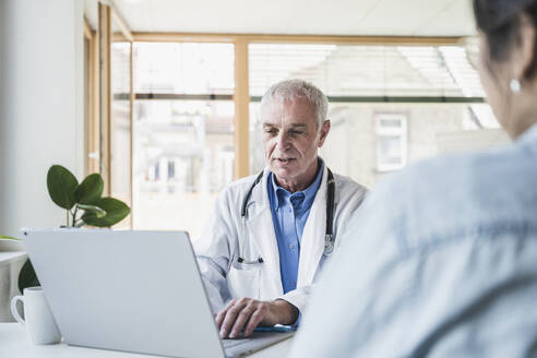 Oberarzt mit Laptop vor einem Patienten in einer medizinischen Klinik - UUF26638