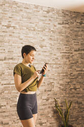 Frau benutzt Smartphone vor einer Wand - MGRF00678