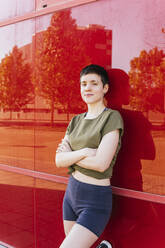 Happy woman with short hair leaning on wall - MGRF00686