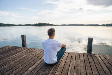 Man looking at scenic view from pier over lake - DIGF18140