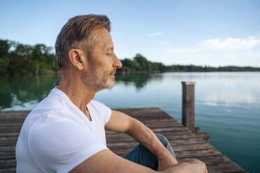 Mature man meditating on jetty - DIGF18141