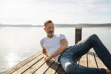 Mature man relaxing on pier at lake - DIGF18168