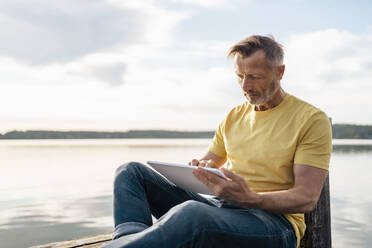 Älterer Mann benutzt Tablet-PC am See - DIGF18181