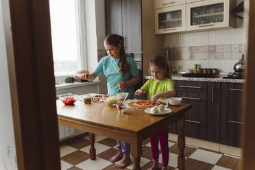 Geschwister machen gemeinsam Pizza in der Küche zu Hause - OSF00177