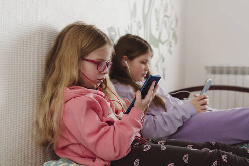 Siblings using mobile phones at home - OSF00180