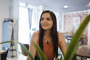 Nachdenkliche junge Geschäftsfrau lächelt im Büro - DCRF01261