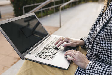 Freelancer wearing checked blazer typing on laptop - JRVF02993