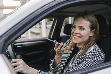 Glückliche Geschäftsfrau, die im Auto sitzend telefoniert - JRVF02995