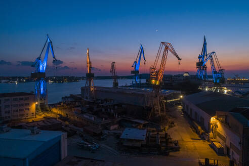 Aerial view of industrial cranes coloured with Ukrainian colours flags in memory of Russian invasion in Ukraine, Pula, Croatia. - AAEF14847