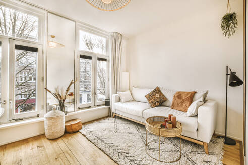 White sofa and coffee table located against windows in living room of modern flat apartment - ADSF35518