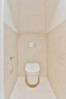 Weiße Keramiktoilette an einer weiß gefliesten Wand mit Dekoration im hellen stilvollen Badezimmer mit leuchtenden Lichtern zu Hause - ADSF35541