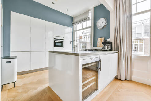 White counters with sink and appliances located against wall with built in furniture in light kitchen at home - ADSF35555