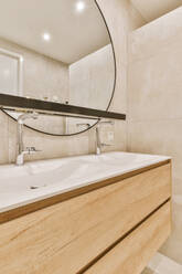 Keramikwaschbecken auf Schubladen unter rundem Spiegel in modernem Bad mit gefliesten Wänden - ADSF35573
