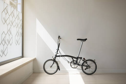 Bicycle leaning on white wall in yoga studio - MTBF01229