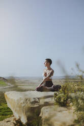 Woman practicing yoga sitting on rock at Bardenas Reales in Spain - MTBF01231