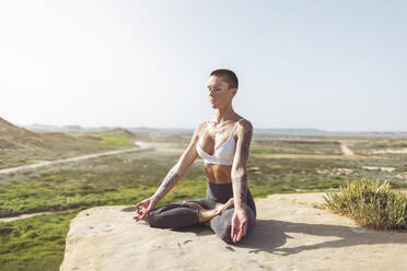 Woman practicing lotus position on rock at Bardenas Reales in Spain - MTBF01234