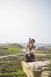 Woman doing yoga sitting on edge of rock at Bardenas Reales in Spain - MTBF01235