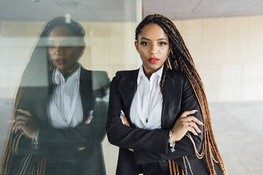 Confident young businesswoman leaning on glass wall - JRVF03014