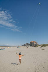 Junge lässt an einem sonnigen Tag am Strand einen Drachen steigen - MFF09152