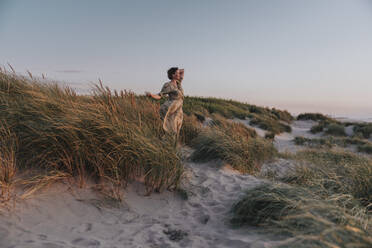 Woman standing amidst plants at sunset - MFF09162