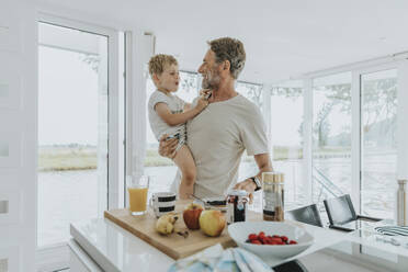 Happy father with son standing by table - MFF09163