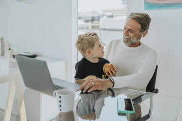 Happy father with son sitting at table - MFF09185