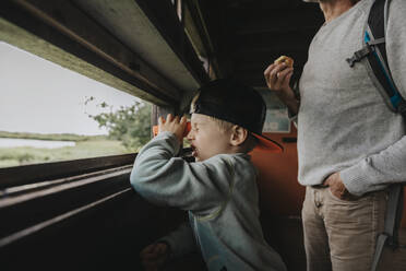 Boy wearing cap looking through binoculars - MFF09216