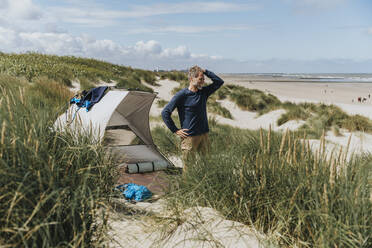 Glücklicher Mann beim Camping an einem sonnigen Tag am Strand - MFF09218