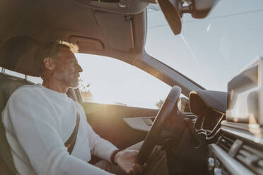 Älterer Mann fährt Auto an einem sonnigen Tag - MFF09233