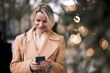 Smiling woman using mobile phone - AGOF00275