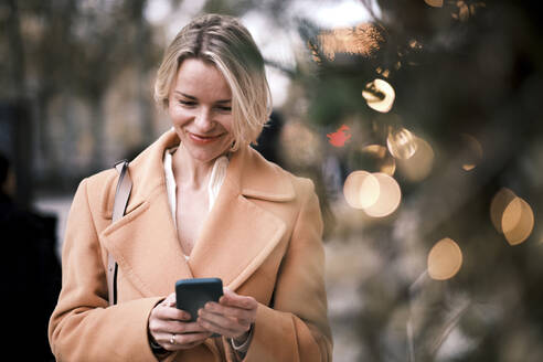 Smiling woman using mobile phone - AGOF00275