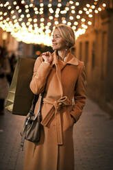 Smiling woman holding shopping bag in city - AGOF00281