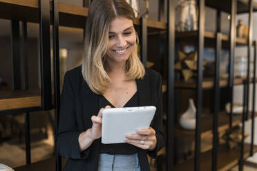 Glückliche Geschäftsfrau mit Tablet-PC in der Hotellobby - JRVF03048