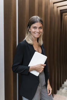 Lächelnde Geschäftsfrau mit Tablet-PC auf dem Hotelflur - JRVF03050