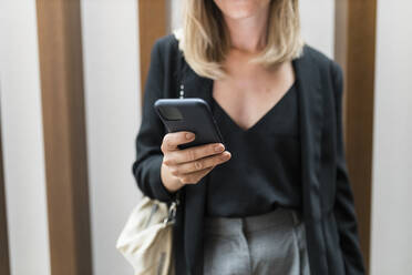 Hände einer Geschäftsfrau, die ein Smartphone im Hotel benutzt - JRVF03056