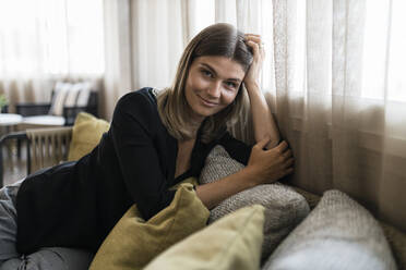 Lächelnde Geschäftsfrau auf dem Sofa im Hotel sitzend - JRVF03063