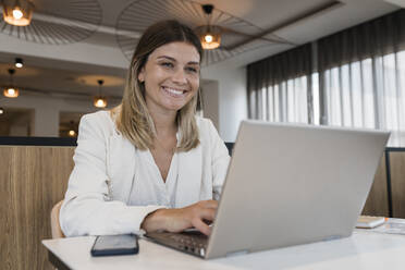 Smiling businesswoman using laptop at restaurant - JRVF03098