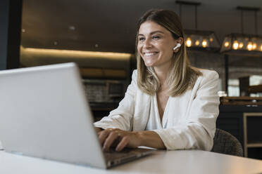 Smiling businesswoman using laptop at restaurant - JRVF03112